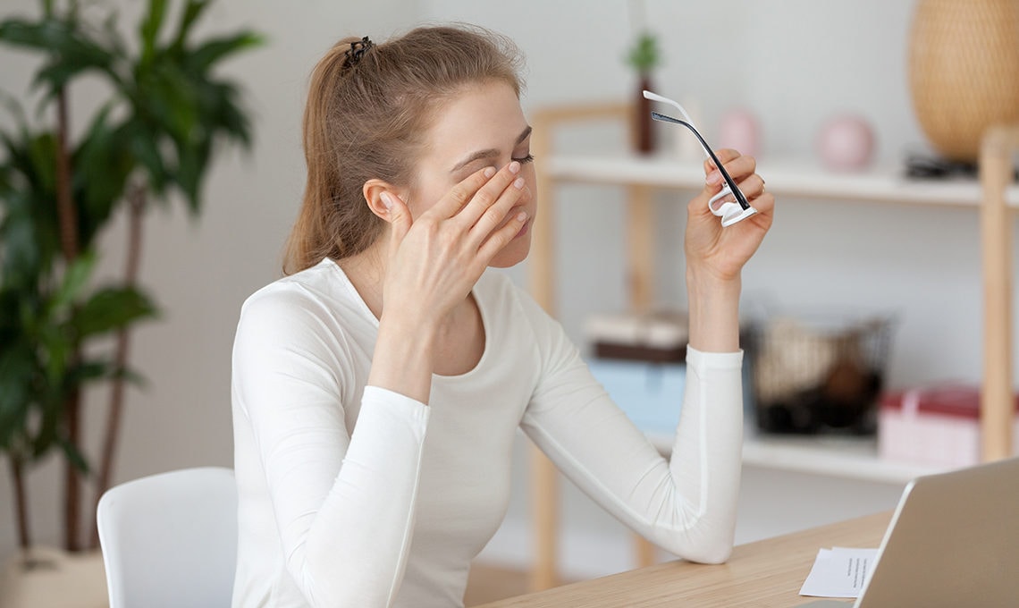 Woman sitting at computer rubbing dry eyes